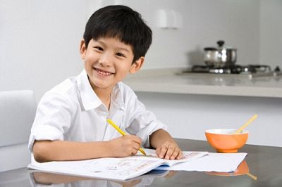 Young boy doing homework in kitchen
